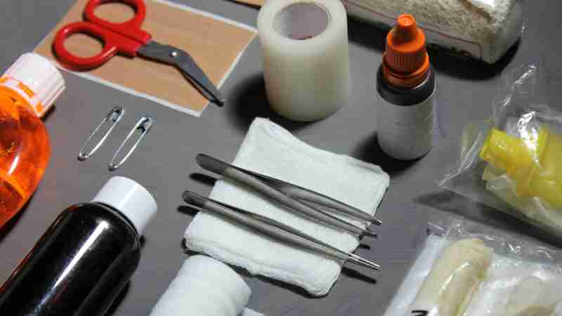 High-angle view of various essential first aid items, including bandages, gauze, scissors, and disinfectants on a table., tags: eerste hulp voor - pexel